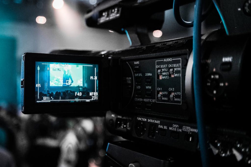 Close-up of a professional video camera recording an event with a stage and audience visible in the viewfinder.Because they demand little effort and low risk, dividend stocks or high-yield savings accounts are the easiest basic passive income investments available