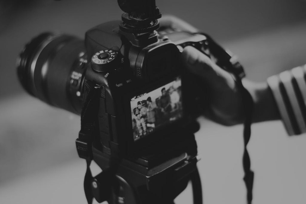 Person with a black DSLR camera in grayscale, highlighting opportunities to market creative content online