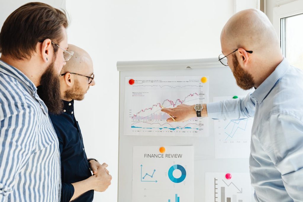 Three professionals discussing a finance report, symbolizing the analysis of a successful digital real estate portfolio.