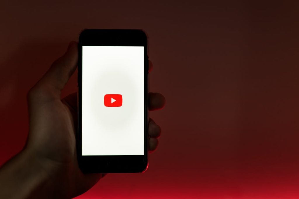 Hand holding smartphone showing YouTube app, illustrating ways to make money on YouTube without filming content