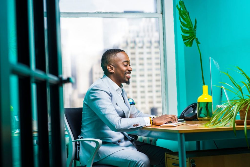 Man in a light blue suit working at a desk in a bright office