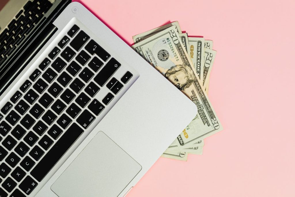 Laptop resting on dollar bills, illustrating how digital course creation can generate real income