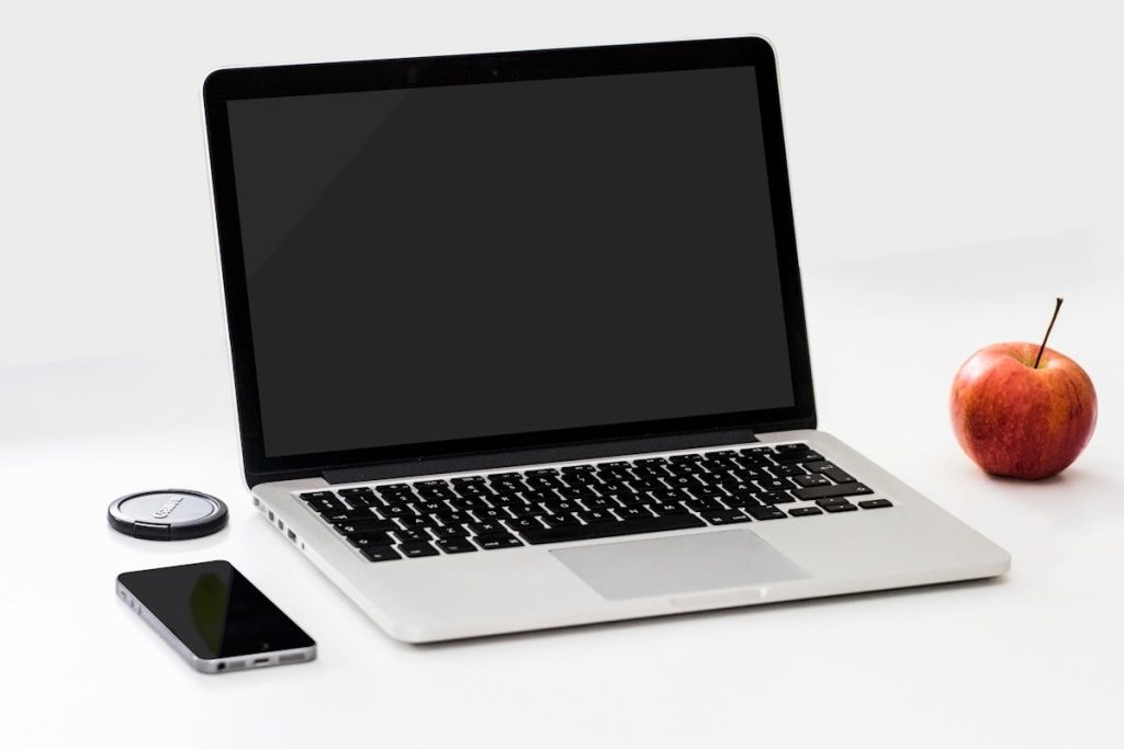 MacBook Pro beside an iPhone and an apple, symbolizing the simplicity and effectiveness of micro-courses over traditional formats