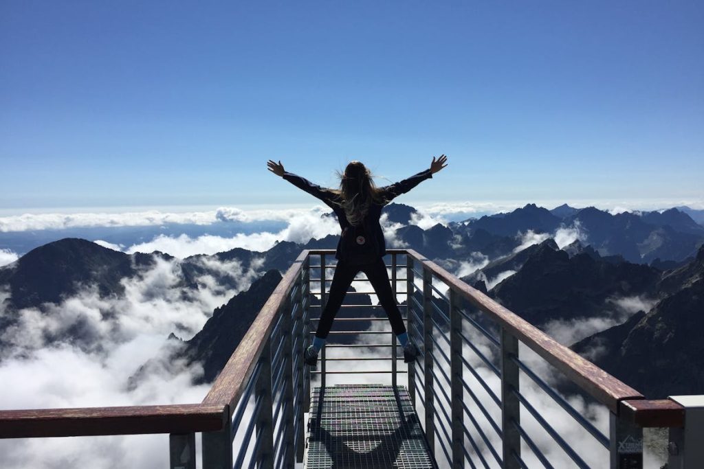 Person standing with arms wide open overlooking mountains, symbolizing success from real-world Invisible Funnel journeys