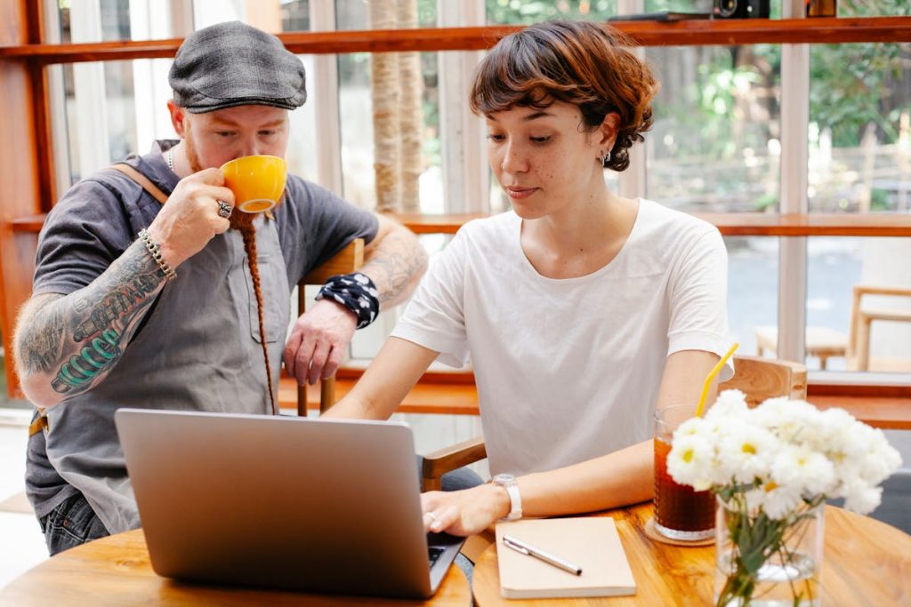 Young woman setting up laptop while man enjoys coffee, illustrating a relaxed Sunday morning dedicated to a 30-minute monetizing setup