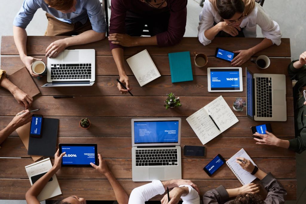 Team collaborating at a wooden table with laptops and tablets