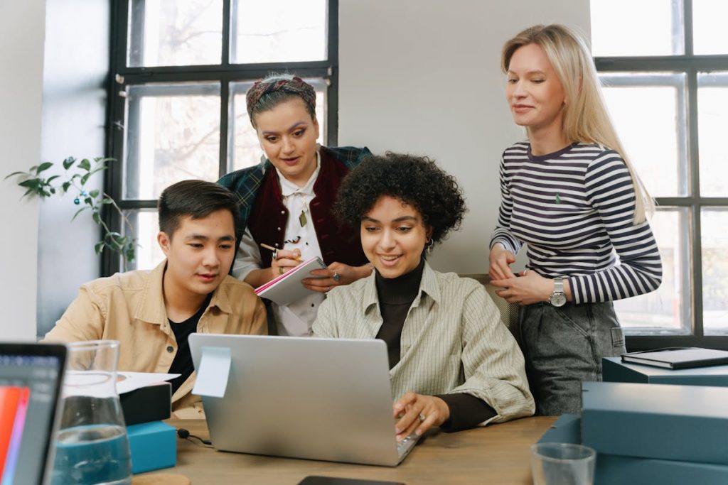 Group of people gathered around a laptop, collaborating on starting an information packaging company
