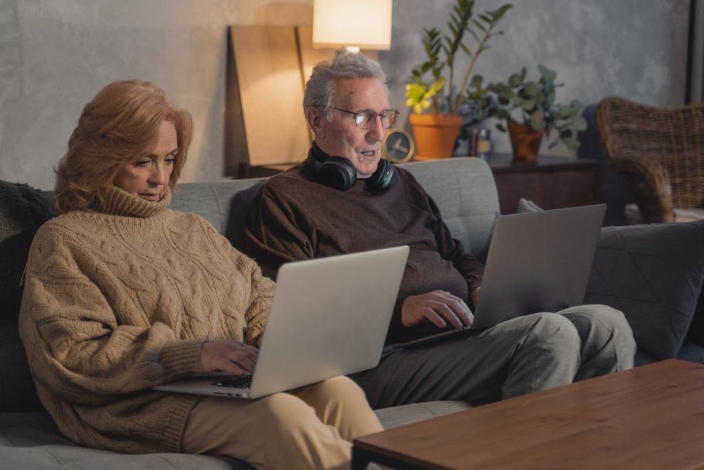 Man and woman sitting on couch using MacBook for tech assistance