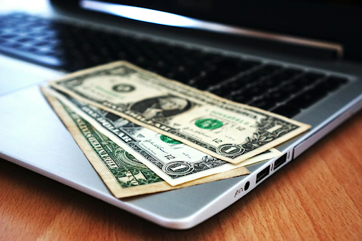 three money bills on top of a laptop