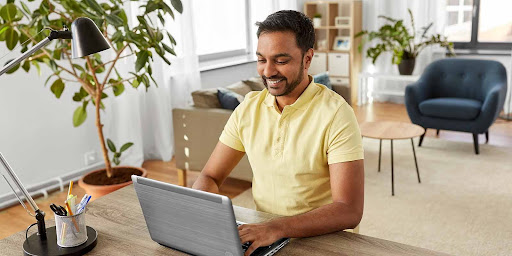 A remote worker smiling while her types on his laptop