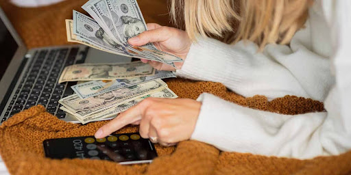 A woman Calculating her income and expenses while with her laptop