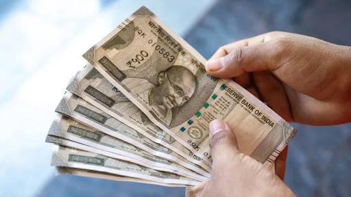 A person holding a bunch of Indian rupee in his hands while counting them