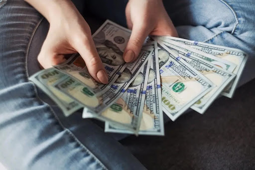 A person holding a stack of $100 dollar bills in his hands