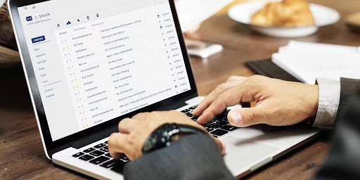 A man wearing a suit typing as he checks his email box