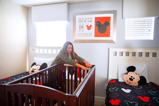 Mother setting up rented baby crib in vacation rental for profitable baby equipment rental side hustle