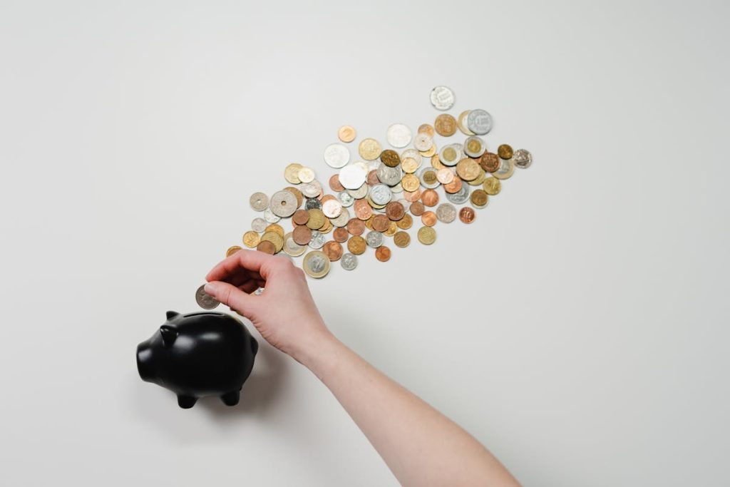 Person placing a coin into a piggy bank, symbolizing smart investing for financial growth