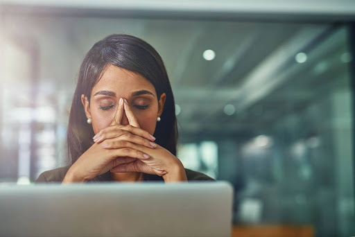 A woman puts her hands on her face with her eyes closed as she thinks