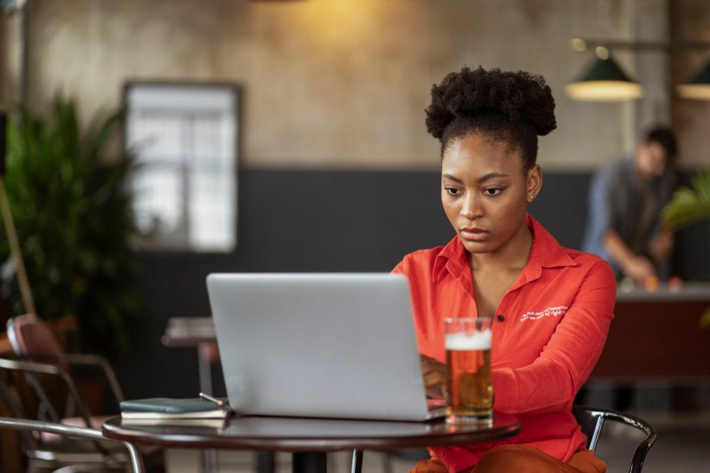 Woman using a laptop in a cafe to grow her side hustle income