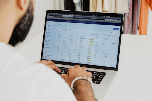A man scrolling through his orders on his store through a laptop