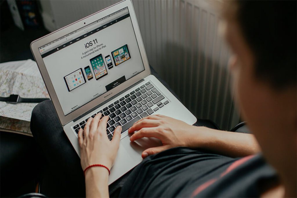 A person sitting on a couch, focused on their laptop, with a cozy living room setting in the background