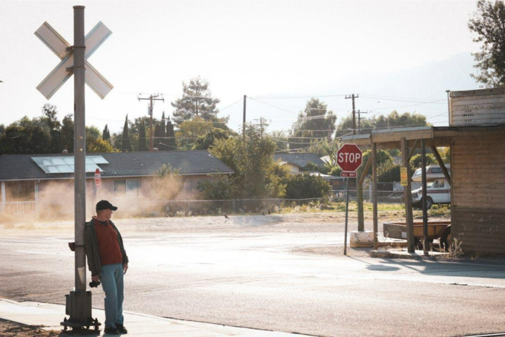 Person standing at a crossroads, one path leading to an office building, the other to a brighter.