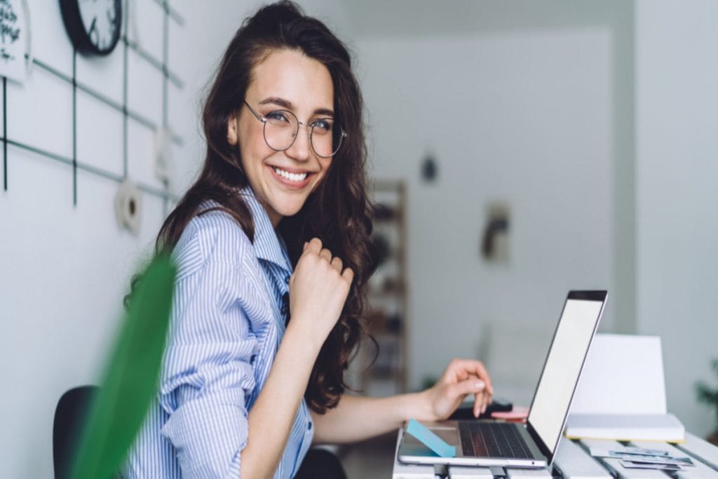 A social media manager at a desk, engaging with social media posts on her laptop