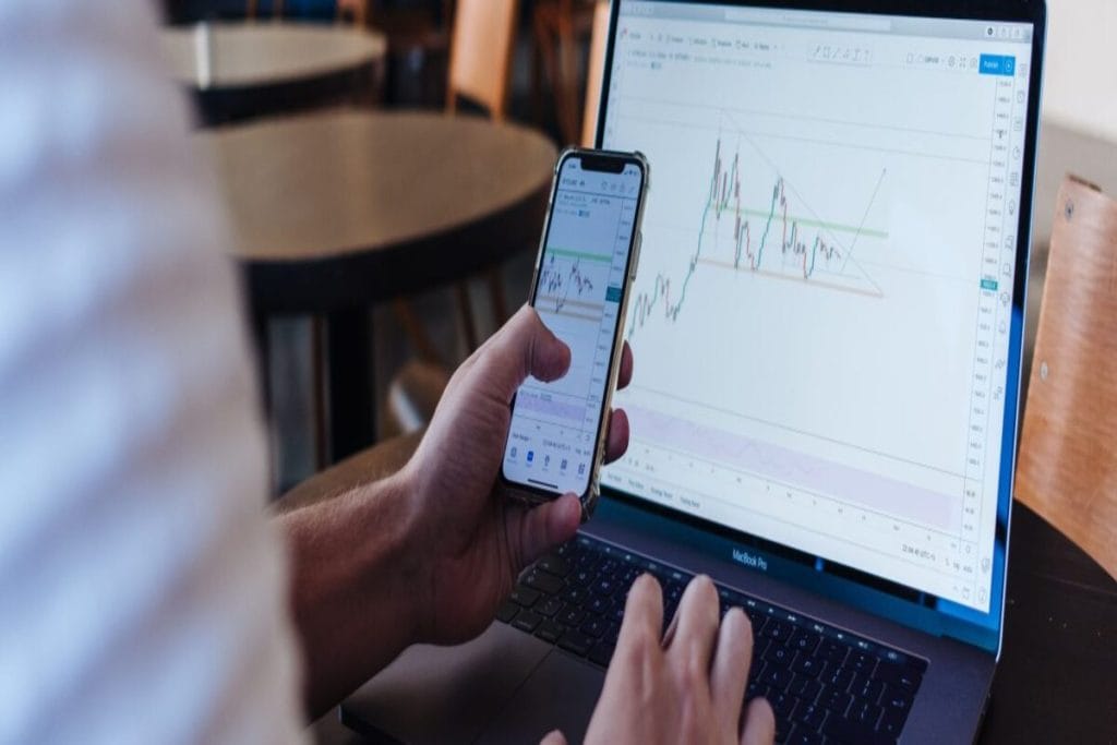 crypto-trader-with-phone-laptop-and-market-chart