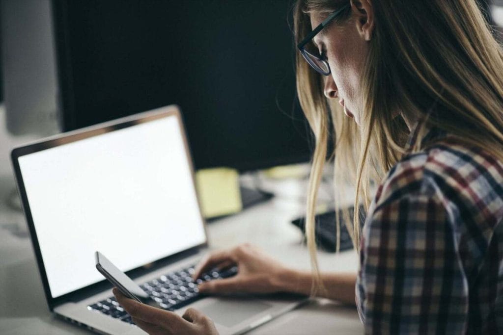 girl-using-laptop-and-phone-side-view